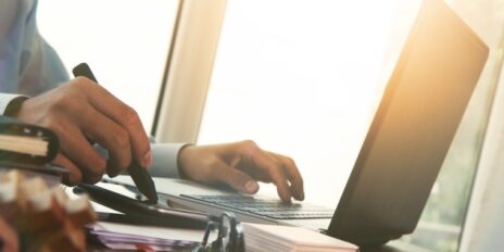 Mann tippt gleichzeitig auf sein Laptop und auf seinen Smartphone.
