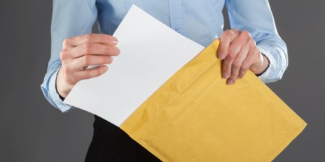 Ein Mann packt seinen Brief in einen gelben Umschlag rein.
