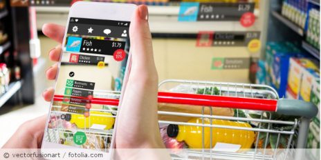 Eine Frau mit einem Handy mit digitalisierten Preisen in einen Supermarkt.