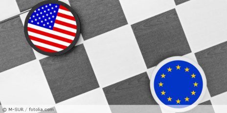 Ein Schachfeld mit zwei runde Chips, mit einer USA-Flagge und einer EU-Flagge.
