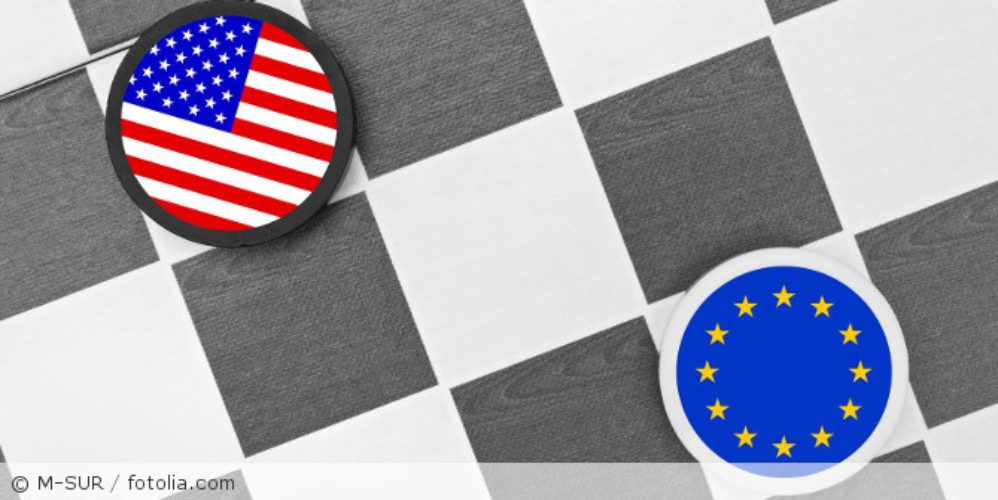 Ein Schachfeld mit zwei runde Chips, mit einer USA-Flagge und einer EU-Flagge.