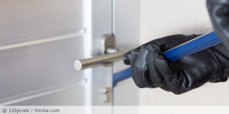 Ein Mann mit Handschuhen der versucht eine Tür aufzubrechen.