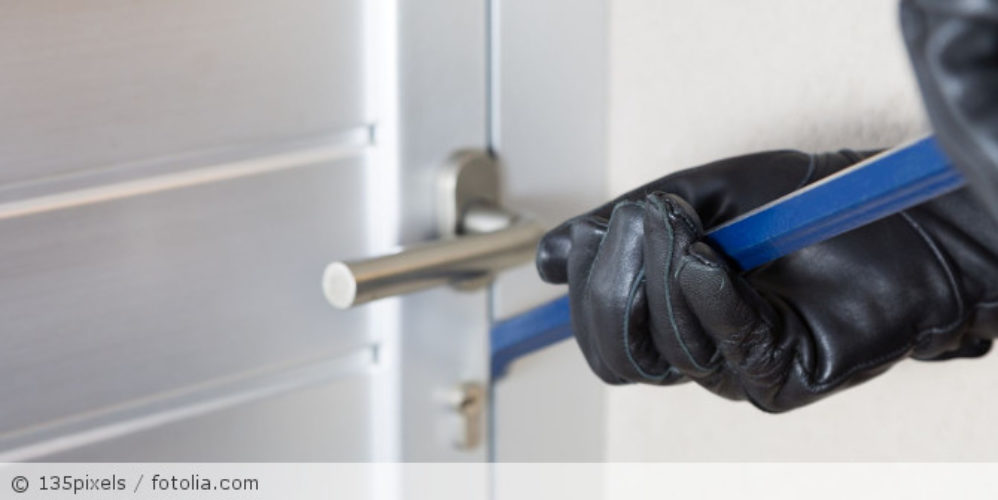 Ein Mann mit Handschuhen der versucht eine Tür aufzubrechen.