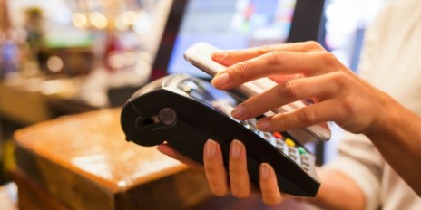 Frau bezahlt ihre Rechnung mit ihrem Smartphone.