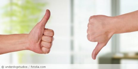 Eine Person zeigt Daumen hoch und die andere Person zeigt Daumen runter.