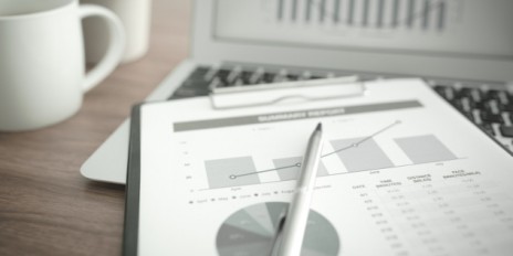 Diagramm hängt an einem Klemmbrett daneben eine Tasse und ein Laptop.