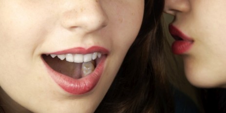 Zwei Frauen die sich ein Geheimnis zuflüstern.
