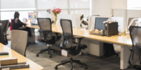 Großraumbüro in dem noch eine Person am Arbeitsplatz sitzt.
