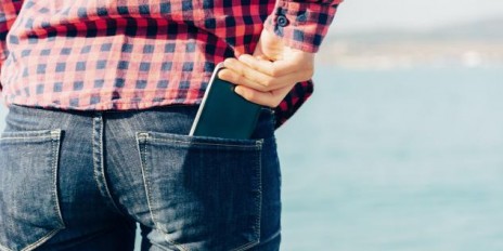 Mann steckt sein Smartphone in seien hintere Hosentasche.
