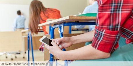 Schüler ist im Unterricht am Handy.