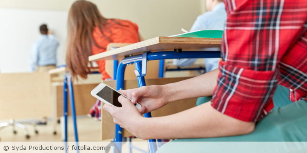 Schüler ist im Unterricht am Handy.