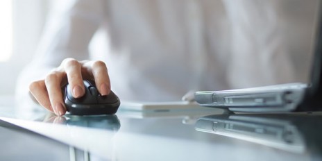 Frau bedient eine Maus und den Computer.