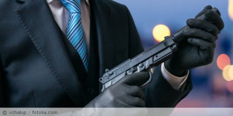 Ein Mann im Anzug mit einer Waffe in der Hand.