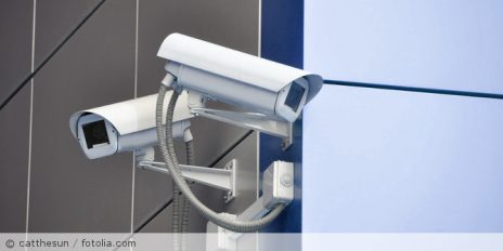 Zwei weiße Überwachungskameras hängen links und rechts an der Wand.