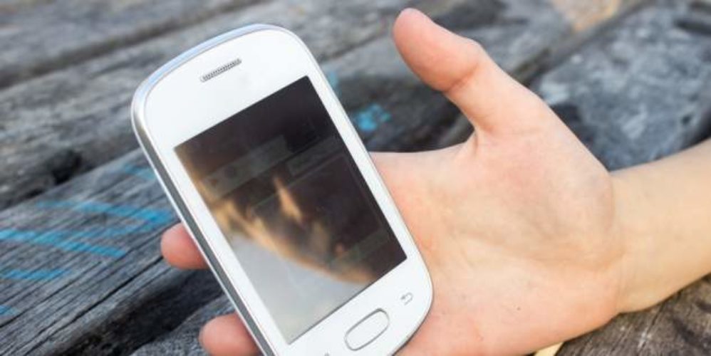 Kind hält sein weißes Smartphone in der Hand.