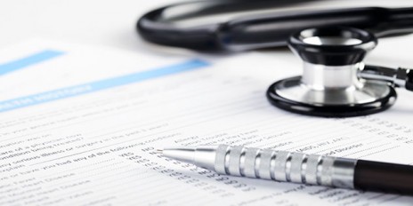 Schwarz grauer Stethoskop und Kugelschreiber liegen auf einem Patientenbogen.