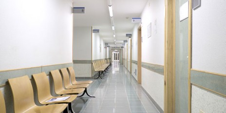 Leeres Krankenhaus mit belichtetem Gang und leeren Stühlen.
