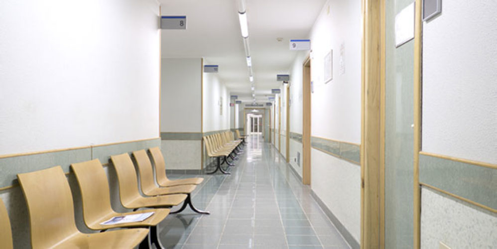 Leeres Krankenhaus mit belichtetem Gang und leeren Stühlen.