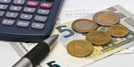 Mindestlohn liegt zusammen mit einem Kugelschreiber, Taschenrechner und einen Kassenbonn auf dem Tisch.