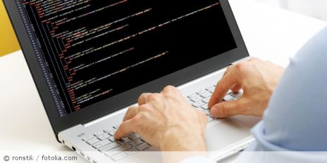 Ein Mann an einen Laptop der etwas programmiert.