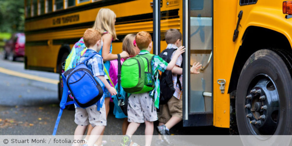 Kinder die in einen Schulbus einsteigen.