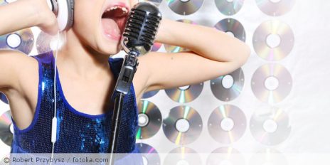 Ein Kind das in ein Mikrofon singt.