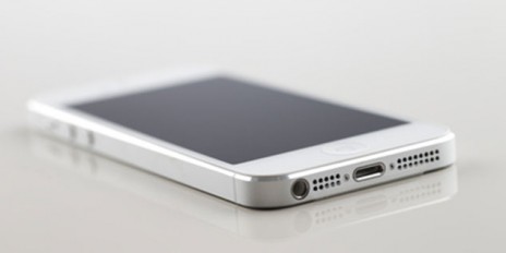 Weißer Smartphone liegt auf einem Weißen Glastisch.