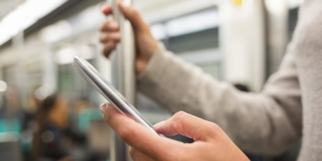 Person in der Bahn und hält den Smartphone in der Hand.