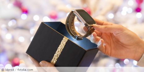 Eine Smartwatch wird aus einer leuchtenden Verpackung geholt.