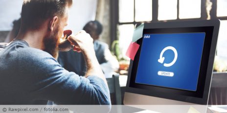 Ein Mann der vor seinem Computer sitzt, auf dem ein Software-Update läuft.