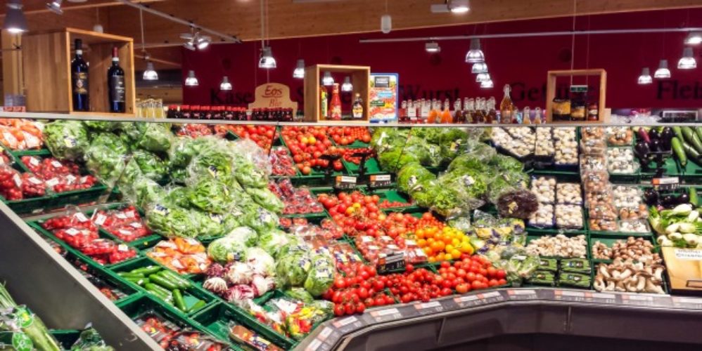 Supermarkt wo die Regale voller Gemüse vollgestellt worden sind.