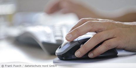 Frau klickt auf die Maus und im Hintergrund ist eine Tastatur.