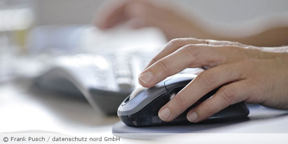 Frau klickt auf die Maus und im Hintergrund ist eine Tastatur.