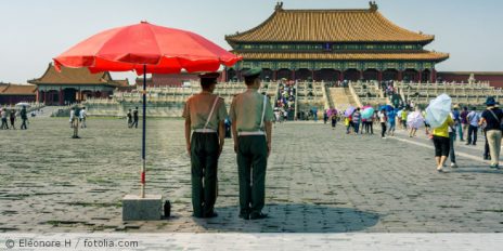 Zwei Wachmänner überwachen Personen auf einen Platz in China.