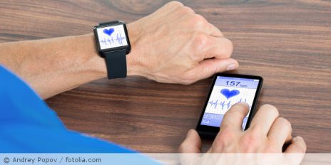 Mann kontrolliert sein Puls auf seiner Smartwatch und seinem Smartphone.