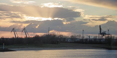 Die Weser mit einem kleinen Strand, wo die Sonne im Hintergrund untergeht.