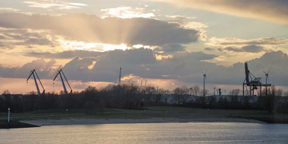 Die Weser mit einem kleinen Strand, wo die Sonne im Hintergrund untergeht.