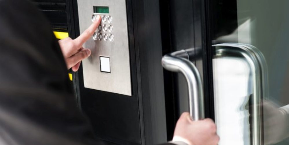 Mann gibt ein Code an der Tür ein um ins Gebäude zu kommen.