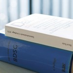 Ein weißes Buch über das Thema Datenschutz liegt auf einem blauen Buch, welches den Titel BDSG beträgt.