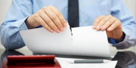 Ein Mann der ein zerrissenes Papier in den Händen hält.
