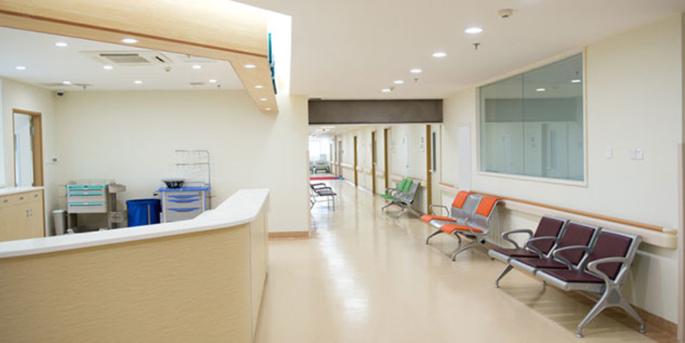 Leeres Krankenhaus mit einer Rezeption und verschiedenfarbigen Stühlen.
