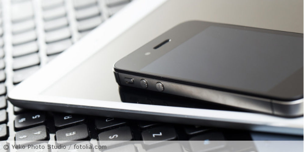 Auf dem Laptop sind gestapelt, ein Ipad und ein Smartphone.