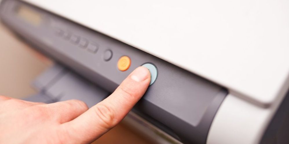 Mann drückt auf ein grünen Knopf am Drucker.