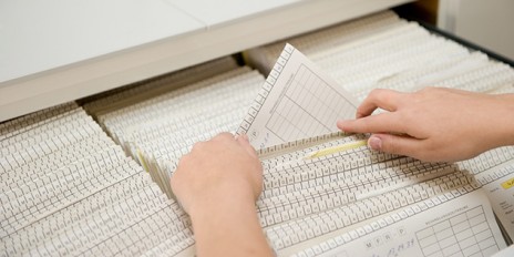 Person sucht einen Patienten in den Akten.