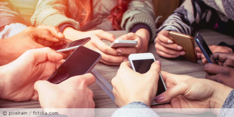 Mehrere Menschen sitzen im Kreis und sind jeweils am Handy.