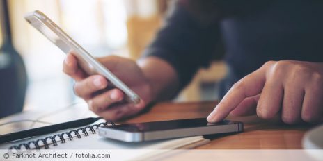 Person bedient zwei Smartphones zur selben Zeit.