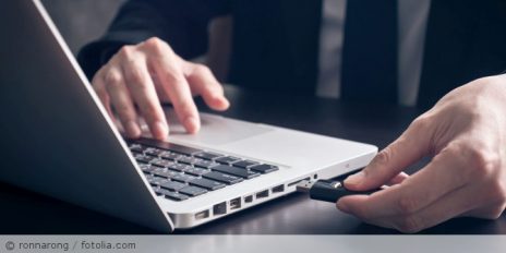 Mann steckt USB-Stick in einen Laptop.