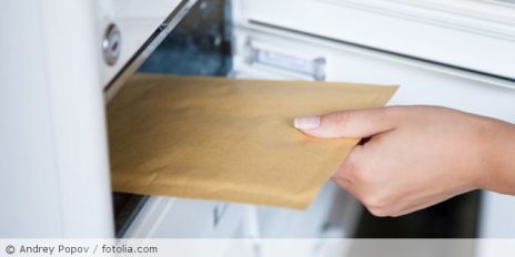 Eine Frau die einen Brief in einen Briefkasten schmeißt.