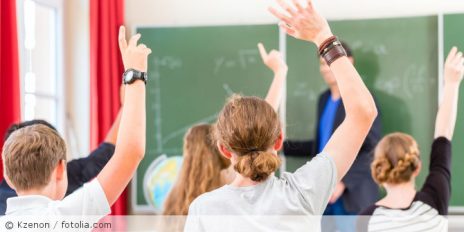 Schüler in einem Klassenzimmer die die Hand heben.