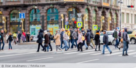 Mehrere Menschen überqueren eine Straße in einer Stadt.